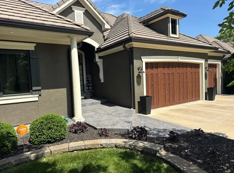 Freshly painted stucco exterior with stained wood-look garage doors and crisp white trim