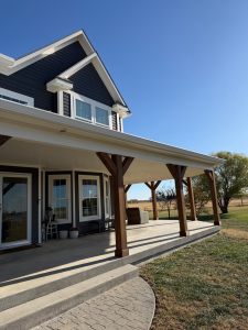 Wrap-around porch with stained cedar posts and freshly painted dark siding