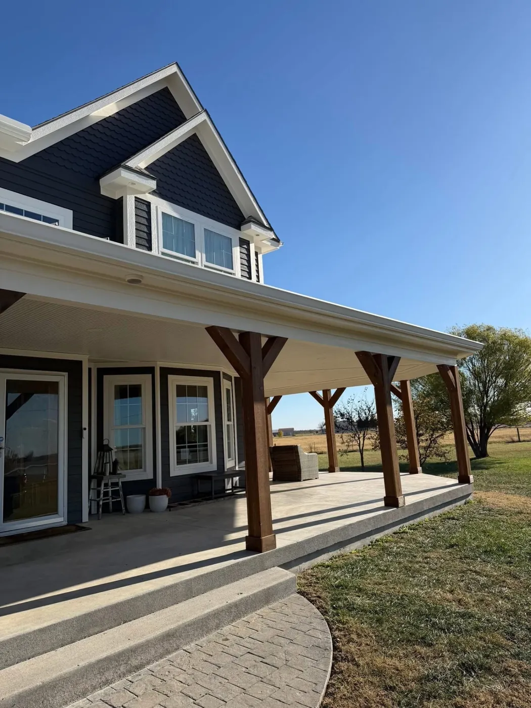 Navy blue farmhouse style home with white trim and a covered front porch with timber posts in the Kansas City area