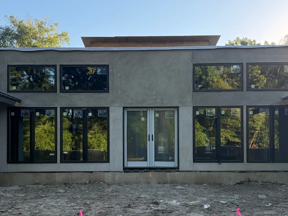 Rear elevation of a Kansas City home with fresh stucco and new windows, ready for priming and paint