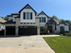 Freshly painted two story Kansas City home with white stone, black trim and garage doors